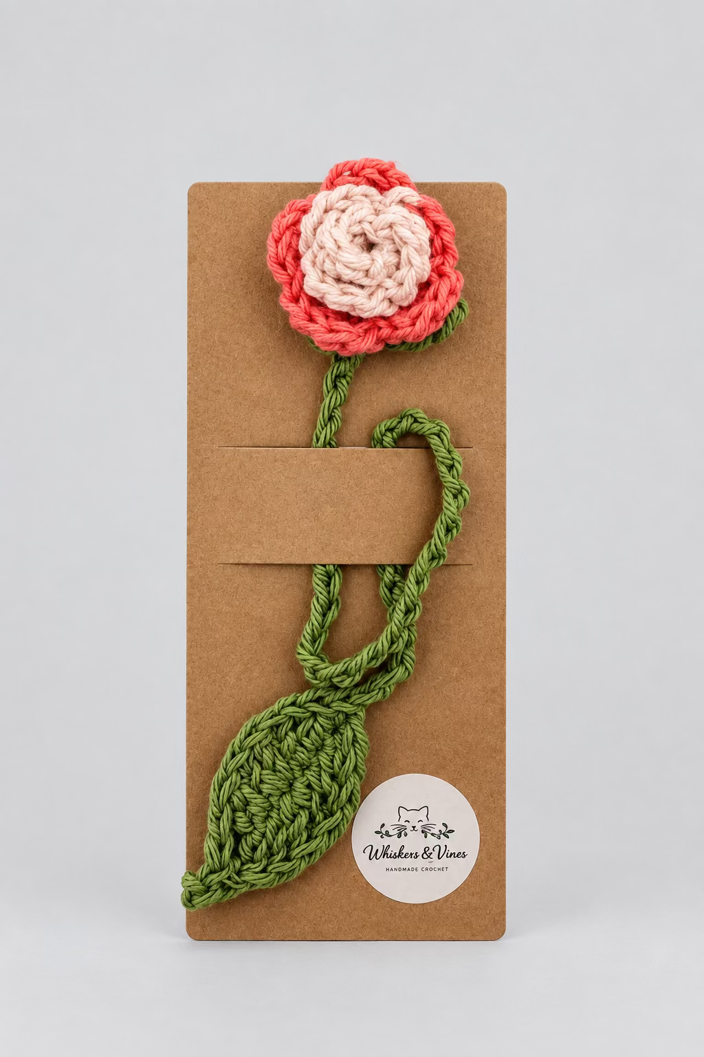 Crocheted flower and leaf on a brown card with a white background