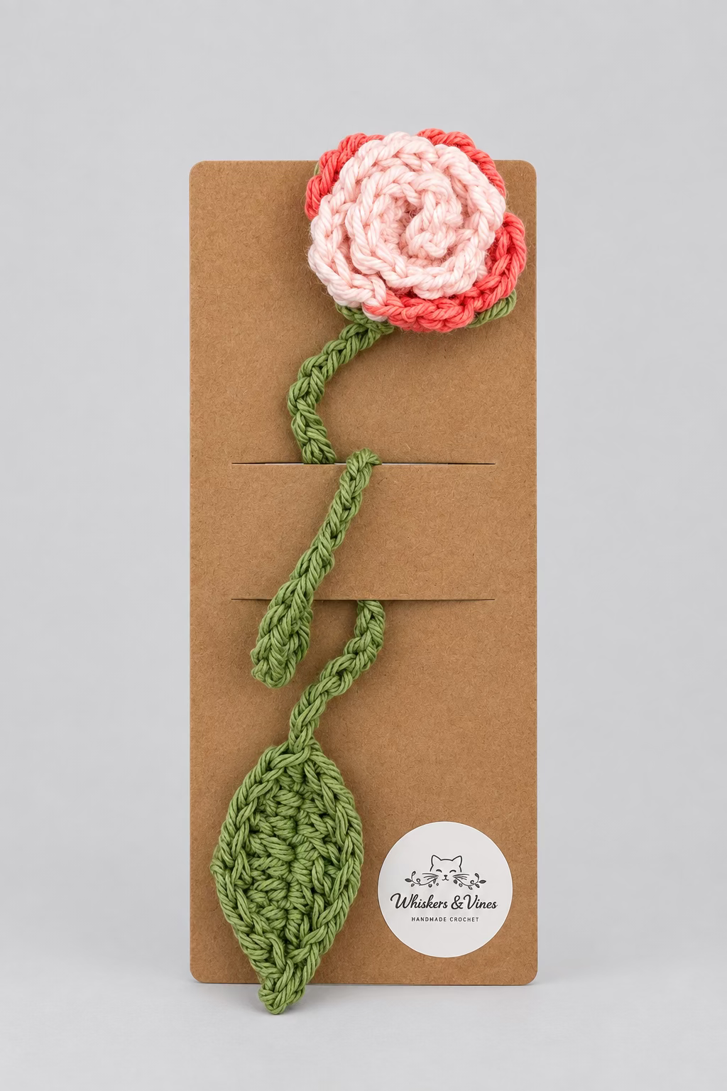 Crocheted flower and leaf on a brown card with a white background